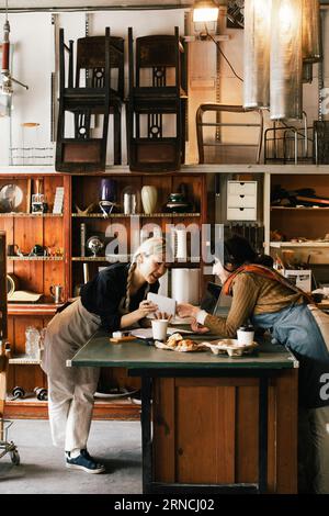 Female coworkers discussing over diary at workbench in upcycling workshop Stock Photo