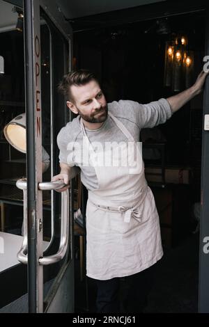 Mature male shop owner peeking at entrance Stock Photo