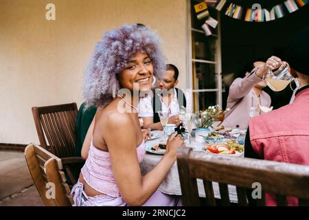Side view portrait of happy transwoman with friends during dinner party in back yard Stock Photo