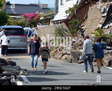 (160417) -- KUMAMOTO, April 17, 2016 -- Residents walk past destroyed buildings in the earthquake rocked Mashiki in Kumamoto prefecture, Japan, April 17, 2016. A powerful magnitude-7.3 earthquake struck the island of Kyushu in southwestern Japan early Saturday just a day after a sizable foreshock hit the region, with the number of fatalities now standing at 41 according to the latest figures on Sunday. ) (djj) JAPAN-KUMAMOTO-EARTHQUAKE-AFTERMATH MaxPing PUBLICATIONxNOTxINxCHN   160417 Kumamoto April 17 2016 Residents Walk Past destroyed Buildings in The Earthquake Rocked Mashiki in Kumamoto Pr Stock Photo