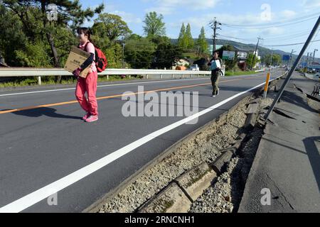 (160417) -- KUMAMOTO, April 17, 2016 -- Residents walk past a damaged road in the earthquake rocked Mashiki in Kumamoto prefecture, Japan, April 17, 2016. A powerful magnitude-7.3 earthquake struck the island of Kyushu in southwestern Japan early Saturday just a day after a sizable foreshock hit the region, with the number of fatalities now standing at 41 according to the latest figures on Sunday. ) (djj) JAPAN-KUMAMOTO-EARTHQUAKE-AFTERMATH MaxPing PUBLICATIONxNOTxINxCHN   160417 Kumamoto April 17 2016 Residents Walk Past a damaged Road in The Earthquake Rocked Mashiki in Kumamoto Prefecture J Stock Photo