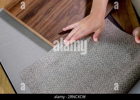 The choice of finishing materials for the design of the house project. The hand of an interior designer selects a palette of sample materials for wall Stock Photo