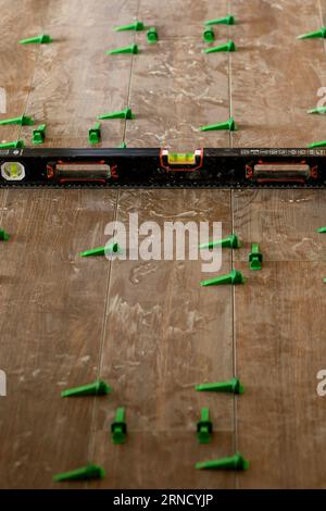 Tile levelling system, four plastic green clips with wedges. Close-up view, selective focus, blurred background. Stock Photo