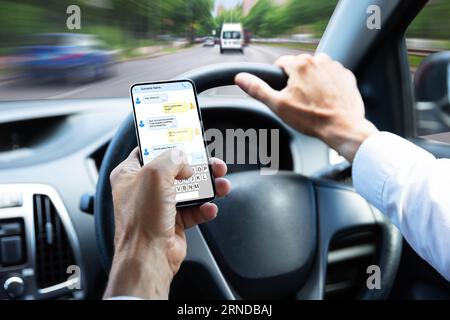 Close-up Of A Man's Hand Typing Text Message On Mobile Phone While Driving Car Stock Photo