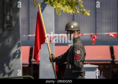 Ankara-Turkey: August 30, 2023: A Turkish soldier holding a Turkey flag on a vehicle during  Parade of soldiers, August 30 ceremony in the street in A Stock Photo