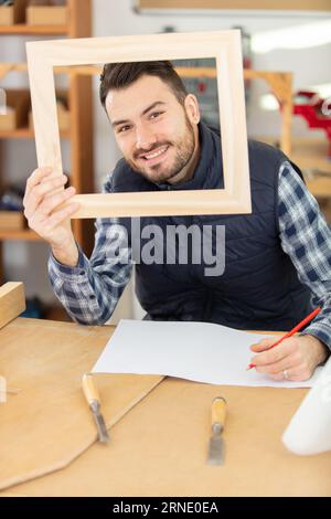 young handsome handyman holding frame Stock Photo
