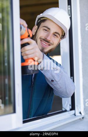 happy man drilling window frame Stock Photo