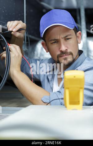 electrician engineer screwing and testing equipment in fuse box Stock Photo