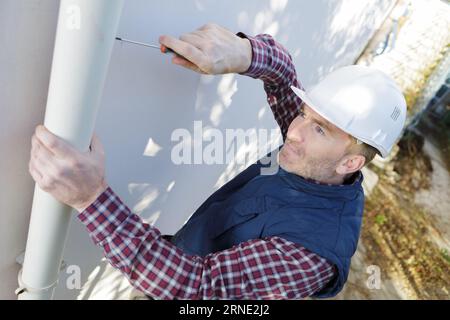 workman replacing guttering on exterior of house Stock Photo
