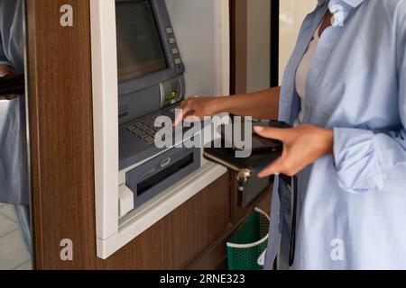 close-up of a woman using an ATM and holding a wallet Stock Photo