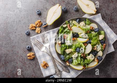 Blueberries, pear, leafy greens salad with walnuts and blue cheese close-up in a plate on the table. horizontal top view from above Stock Photo