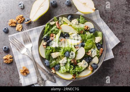 Fresh diet salad with blueberries, lettuce, gorgonzola cheese, walnuts and pear close-up in a plate on the table. horizontal top view from above Stock Photo
