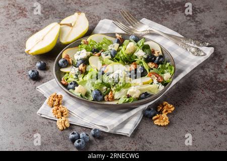 Blueberries, pear, leafy greens salad with walnuts and blue cheese close-up in a plate on the table. horizontal Stock Photo