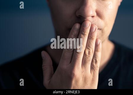 Oops, secret gossip. Lips sealed, mute. Surprise, shock. Quiet shy man cover mouth with hand. Censorship, freedom of speech or taboo concept. Stock Photo