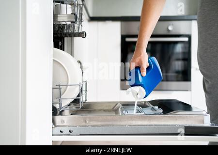 Dish washing powder. Dishwasher detergent and soap. Man loading washer machine. Dirty plates. Household technology for domestic family chores. Stock Photo