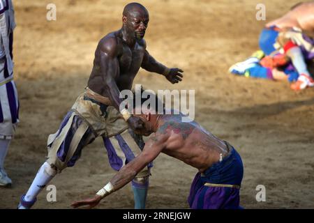 Florenz: Historisches Fußballspiel Calcio Fiorentino A Santo Spirito Bianchi player (white) fights against a La Santa Croce Azzuri player during the Calcio Fiorentino (historic football) final match in Santa Croce square, Florence, central Italy, June 24, 2016. Calcio Fiorentino, an early form of football from the 16th century, originated from the ancient roman harpastum . Played in teams of 27, using both feet and hands, rules allows tactics such as head-butting, punching, elbowing, and choking, but forbids sucker-punching and kicks to the head. Goals are scored by throwing the ball over a go Stock Photo