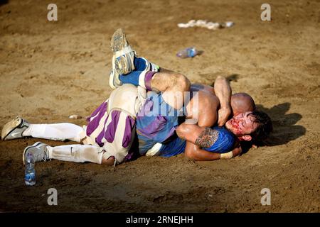 Florenz: Historisches Fußballspiel Calcio Fiorentino A Santo Spirito Bianchi player (White) fights against a La Santa Croce Azzuri player during the Calcio Fiorentino (historic football) final match in Santa Croce square, Florence, central Italy, June 24, 2016. Calcio Fiorentino, an early form of football from the 16th century, originated from the ancient roman harpastum . Played in teams of 27, using both feet and hands, rules allows tactics such as head-butting, punching, elbowing, and choking, but forbids sucker-punching and kicks to the head. Goals are scored by throwing the ball over a go Stock Photo