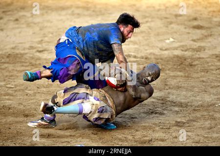 Florenz: Historisches Fußballspiel Calcio Fiorentino A Santo Spirito Bianchi player (White) fights against a La Santa Croce Azzuri player during the Calcio Fiorentino (historic football) final match in Santa Croce square, Florence, central Italy, June 24, 2016. Calcio Fiorentino, an early form of football from the 16th century, originated from the ancient roman harpastum . Played in teams of 27, using both feet and hands, rules allows tactics such as head-butting, punching, elbowing, and choking, but forbids sucker-punching and kicks to the head. Goals are scored by throwing the ball over a go Stock Photo