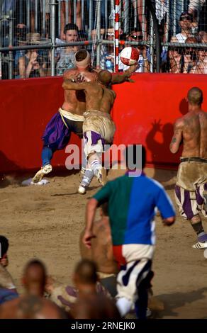 Florenz: Historisches Fußballspiel Calcio Fiorentino A La Santa Croce Azzuri player scores during the Calcio Fiorentino (historic football) final match against the Santo Spirito Bianchi in Santa Croce square, Florence, central Italy, June 24, 2016. Calcio Fiorentino, an early form of football from the 16th century, originated from the ancient roman harpastum . Played in teams of 27, using both feet and hands, rules allows tactics such as head-butting, punching, elbowing, and choking, but forbids sucker-punching and kicks to the head. Goals are scored by throwing the ball over a goal running th Stock Photo