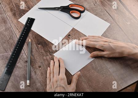 hands of an elderly woman fold origami paper. Creating an origami paper crane, close-up Stock Photo