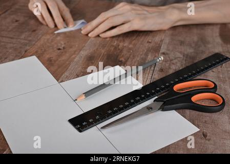 hands of an elderly woman fold origami paper. Creating an origami paper crane, close-up Stock Photo