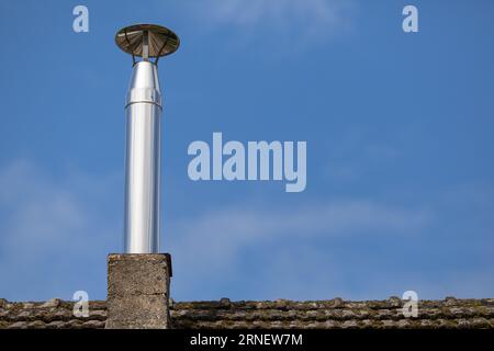 steel pipe of roof chimney without smoke exhausts waste gas from traditional heater out of home and blows it in the air Stock Photo