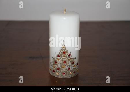 A white candle with gold designs on it. Stock Photo