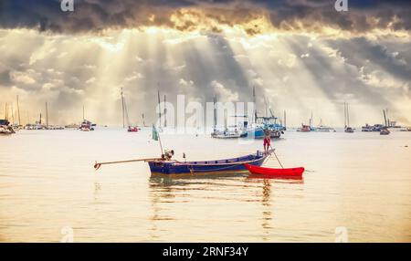 A local brings his boat home after a day of touring with tourists . In the background you can see many boats, some touched by the sun's rays coming th Stock Photo