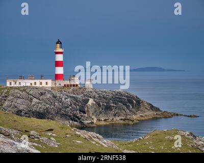 Looking out across the Minch to the Isle of Skye, the red and white Eilean Glas Lighthouse on the east coast of the island of Scalpay in the Outer Heb Stock Photo