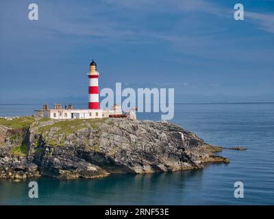 Looking out across the Minch to the Isle of Skye, the red and white Eilean Glas Lighthouse on the east coast of the island of Scalpay in the Outer Heb Stock Photo