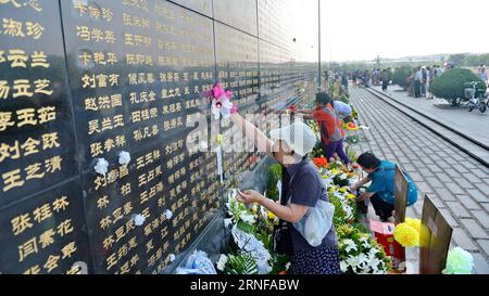 (160728) -- TANGSHAN, July 28, 2016 -- A woman pastes paper flowers beside the name of her relative killed in the 1976 Tangshan earthquake listed on a memorial wall in Tangshan, north China s Hebei Province, July 28, 2016. Local residents came to the Tangshan Earthquake Ruins Memorial Park on Thursday to mark the 40th anniversary of the devastating earthquake that killed their family members and friends. )(wsw) CHINA-HEBEI-TANGSHAN-EARTHQUAKE-COMMEMORATION (CN) MouxYu PUBLICATIONxNOTxINxCHN   160728 Tang Shan July 28 2016 a Woman pastes Paper Flowers Beside The Name of her relative KILLED in T Stock Photo