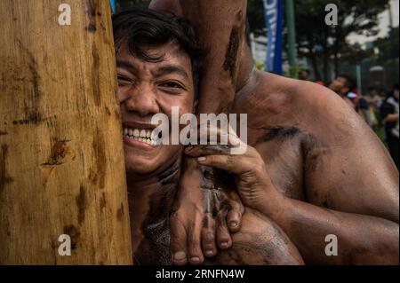 Unabhängigkeitstag in Indonesien (160817) -- JAKARTA, Aug. 17, 2016 -- A man reacts while his team member steps on his shoulder during pole climbing to celebrate the 71st Indonesian Independence Day in Jakarta, Indonesia, on Aug. 17, 2016. Every year people around Jakarta city climb hundreds of poles, trying to get prizes on the top of the poles to celebrate the Indonesian Independence Day. ) (wtc) INDONESIA-JAKARTA-INDEPENDENCE DAY-CELEBRATION-POLE CLIMBING VerixSanovri PUBLICATIONxNOTxINxCHN   Independence Day in Indonesia 160817 Jakarta Aug 17 2016 a Man reacts while His Team member Steps O Stock Photo