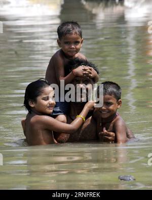 Bilder des Tages Überschwemmungen in Indien (160822) -- PATNA, Aug. 21, 2016 -- A man holding his children wades through a flooded road on the outskirts of Patna, capital of eastern Indian state of Bihar, on Aug. 21, 2016. India s holy river Ganges flowed above the danger level due to incessant rainfall in Bihar in the last few days. ) (syq) INDIA-PATNA-GANGES-FLOOD Stringer PUBLICATIONxNOTxINxCHN   Images the Day Flooding in India 160822 Patna Aug 21 2016 a Man Holding His Children Wade Through a flooded Road ON The outskirts of Patna Capital of Eastern Indian State of Bihar ON Aug 21 2016 In Stock Photo