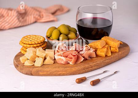 Food photography of antipasto, red wine, cheese, ham, serrano, olive, prosciutto, bacon, parmesan, cheddar, cracker Stock Photo