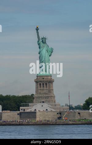 A frontal view of the statue of liberty, with hundreds of tourists around it. Stock Photo
