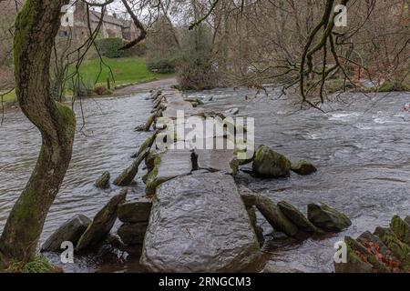 Ancient man made clapper bridge across a fast flowing ford in te Winter time when the water is high Stock Photo