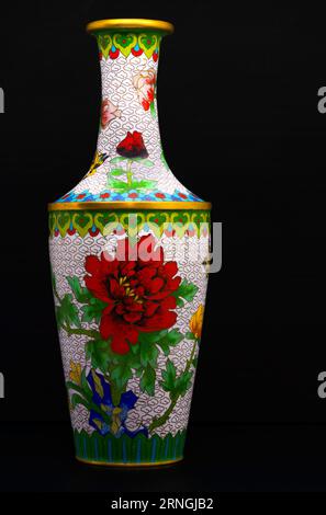 A high-resolution photograph of a brightly and beautifully ornamented cloisonné vase, adorned with red, yellow, blue, and pink flowers, accented with Stock Photo
