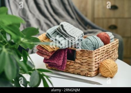 Hand-knitted woolen socks of different colors in a wicker basket on a coffee table close-up Stock Photo
