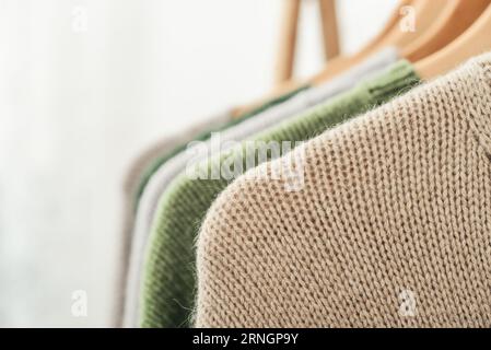 Multicolored handknitted sweaters on hangers closeup. Fashion concept. Stock Photo
