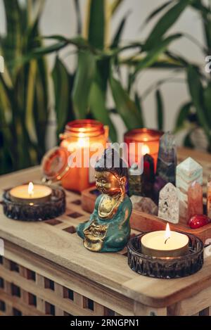 Various minerals and healing crystals on a wooden tray, buddha statuette and candles close-up. Meditation concept. Stock Photo