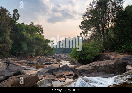 On the Pakse Loop route,long exposure water motion,over wonderful rock formations and large shining boulders,looking into the sunset along the Vang Ng Stock Photo