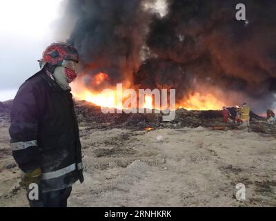 Irak: Brennendes Ölfeld in Qayyarah (161126) -- QAYYARAH, Nov. 26, 2016 -- Oil company workers try to put off fire at an oil well in Qayyarah town, south of Mosul, in northern Iraq, on Nov. 26, 2016. Qayyarah town is seized by the Islamic State (IS) militants in June of 2014. The IS militants bombed all oil wells here when Iraqi army recaptured the town in August this year. The army started military operations to retake Mosul city on Oct. 17, since when the government organized oil companies to put off the fire. Due to poor security situation and equipment, several oil wells are still on fire Stock Photo