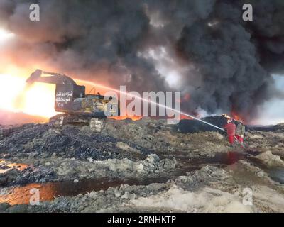 Irak: Brennendes Ölfeld in Qayyarah (161126) -- QAYYARAH, Nov. 26, 2016 -- Oil company workers try to put off fire at an oil well in Qayyarah town, south of Mosul, in northern Iraq, on Nov. 26, 2016. Qayyarah town is seized by the Islamic State (IS) militants in June of 2014. The IS militants bombed all oil wells here when Iraqi army recaptured the town in August this year. The army started military operations to retake Mosul city on Oct. 17, since when the government organized oil companies to put off the fire. Due to poor security situation and equipment, several oil wells are still on fire Stock Photo