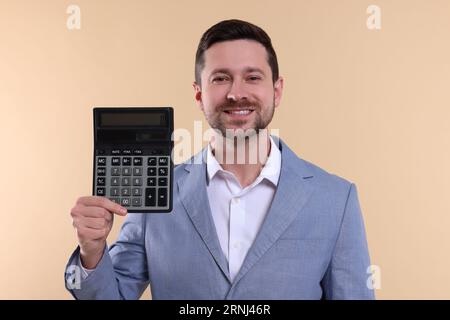 Happy accountant with calculator on beige background Stock Photo