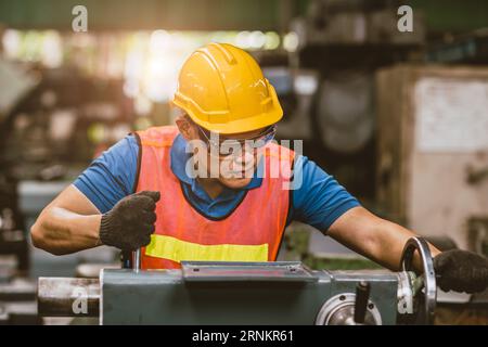 Young Asian Technician Engineer Staff Worker using Lathe CNC Milling Machine work in Heavy Metal Factory. Stock Photo