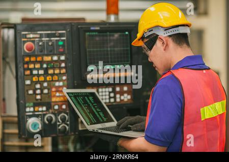 Smart Engineer programmer service panel program operate CNC lathe milling machine with laptop computer fix repair old machine. Stock Photo