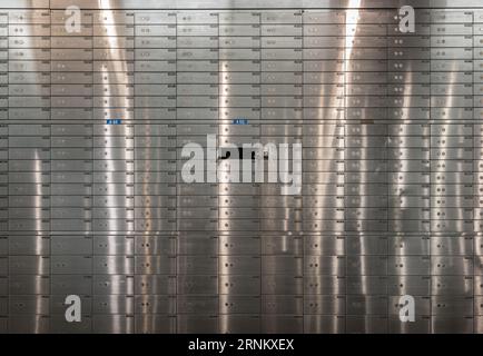 Safe deposit boxes inside bank vault with closed steel doors. Metal deposit lockers, Open deposit box with key, Space for text, Selective focus. Stock Photo