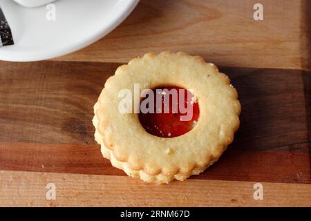 Traditional Linzer Christmas cookie (Linecke pecivo) filled with strawberry jam on wooden board Stock Photo