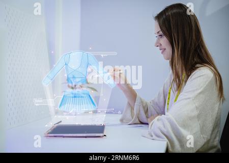 Costume fashion clothing designer using 3D hologram VR visual digital design technology in tailor studio Stock Photo