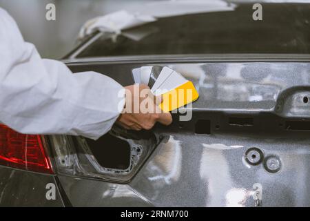 car body painter painting select paint colors using sample card for pick choice color shade in auto garage body workshop Stock Photo